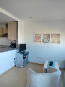 a white living room with a couch and a tv at Condado de alhama, naranjos 8 in Alhama de Murcia