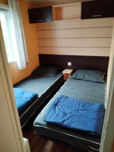 two beds in a room with blue sheets at MOBIL HOME 43 dans Camping 4 Etoiles in Gastes