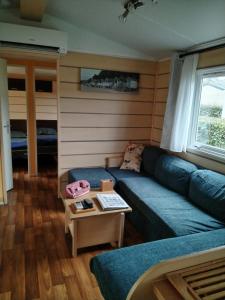 un soggiorno con divano blu e tavolo di MOBIL HOME 43 dans Camping 4 Etoiles a Gastes