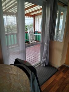 Schlafzimmer mit einer Tür, die auf eine Terrasse mit einem Stuhl führt in der Unterkunft MOBIL HOME 43 dans Camping 4 Etoiles in Gastes
