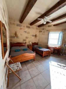 a bedroom with two beds and a ceiling fan at Gozo Silence in Għarb