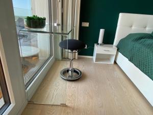 a stool in a room with a bed and green walls at ALPEN-PANORAMA SUITE - Einzigartige Privatsuite hoch über München, 12tes OG, Alpenblick, Loggia, Whirlpool, 15 Minuten zum Zentrum, Ruhe und Erholung in der Stadt München für privat und geschäftlich Reisende in Munich