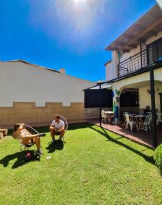 Ein Mann und eine Frau sitzen im Garten in der Unterkunft Fuxia House Hostel in Mendoza