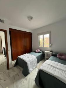 a bedroom with two beds and a window at Gran Chalet a 13 min de Sevilla in Gelves