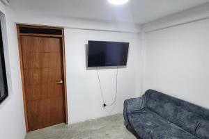 sala de estar con sofá y TV en la pared en La Duna de Emy en Ica