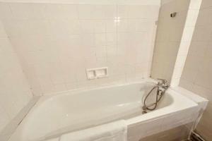 uma banheira branca numa casa de banho com azulejos brancos em 41m love nest for a pleasant stay in Lyon em Lyon