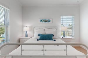Dormitorio blanco con cama blanca y almohada azul en New Home 3br/25br w/ kayak access sleeps 9, en Orange Beach