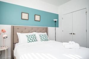 a bedroom with a white bed with a blue wall at Brand-new Parkview with Balcony in Old Fourth Ward 542Blvd203 in Atlanta