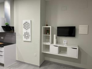 een woonkamer met een tv en een witte muur bij Garden City Lofts in Córdoba