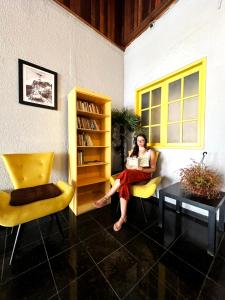 a woman sitting on a chair reading a book at HMG - Praia de Botafogo in Rio de Janeiro