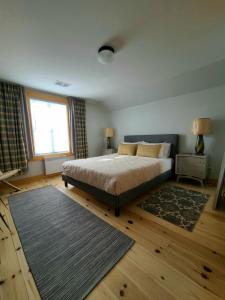 una camera con letto, finestra e tappeto di La Petite Auberge Sur Queen a Rawdon