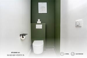 a bathroom with a white toilet in a green wall at Beauquartier - Marais Vertus in Paris +91 photos