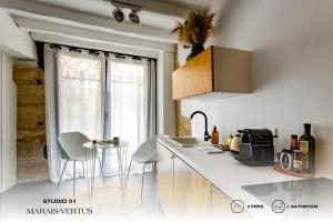een keuken met witte werkbladen en een tafel en een raam bij Beauquartier - Marais, Vertus in Parijs