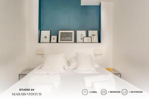 a bedroom with a white bed with pictures on the wall at Beauquartier - Marais Vertus in Paris