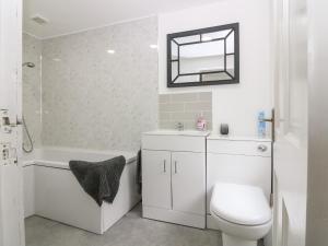 a white bathroom with a toilet and a sink at RockStar Cottage in Macduff +27 photos