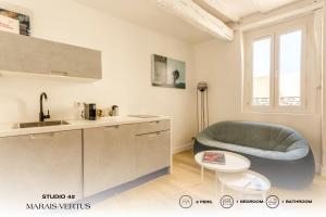 Beauquartier - Marais, Vertus في باريس: مطبخ مع أريكة زرقاء وطاولة