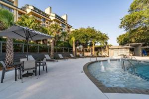 a pool with chairs and an umbrella next to a building at 1408 Ocean Club by AvantStay Oceanfront Home w Amazing Views in Isle of Palms