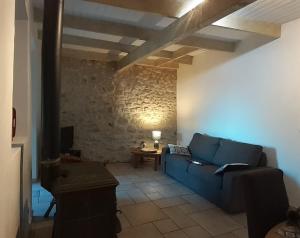 a living room with a blue couch and a stone wall at Gîte de la font d'Arlane in Viviers