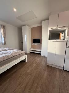a white bedroom with a bed and a television at RK Apartment Holzova in Líšeň