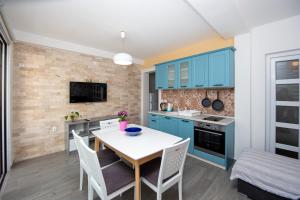 cocina con armarios azules, mesa y sillas en Apartments AriaSana, en Dobra Voda