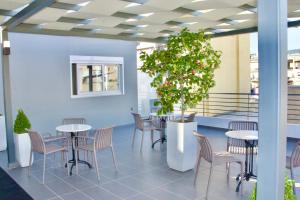 ein Zimmer mit Tischen, Stühlen und einem Topfbaum in der Unterkunft Piraeus Relax in Piräus