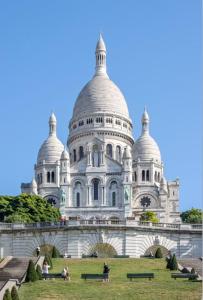 Un grand bâtiment blanc avec des gens debout dans l'herbe dans l'établissement La parisienne, à Le Raincy