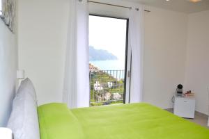 um quarto com uma cama verde e uma grande janela em Amalfi Montemare Rooms em Amalfi