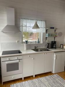 Sandöverken的住宿－Lövlingskulle，厨房配有白色橱柜、水槽和窗户。