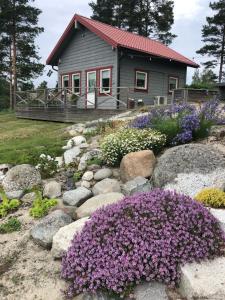 une petite maison avec des fleurs violettes devant elle dans l'établissement Lövlingskulle, à Sandöverken