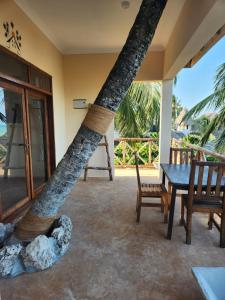 Zimmer mit einem Tisch, Stühlen und einem Baum in der Unterkunft Two Palms in Jambiani