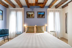 a bedroom with a large white bed with two windows at Ca' dell'Arciere Apartments in Venice