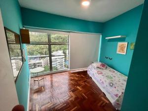 Esplêndido e Aconchegante في ريو دي جانيرو: غرفة نوم بجدران زرقاء وسرير وطاولة