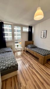 two beds in a room with wooden floors and windows at Warszawa Centrum Pokoje in Warsaw