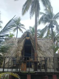 Cabaña con techo de paja, sillas y palmeras en SakaNibue en San Bernardo del Viento