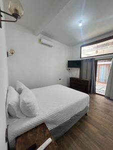 MAYAN SURF HOTEL في El Paredón Buena Vista: غرفة نوم بسرير وملاءات بيضاء ونافذة