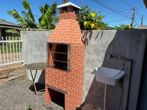 a brick oven with a sink in a backyard at Chalé hespanhol 01 in Passo de Torres