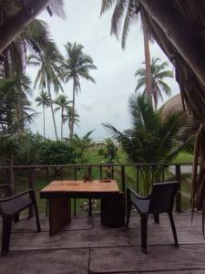 einen Holztisch und Stühle auf einer Terrasse mit Palmen in der Unterkunft SakaNibue in San Bernardo del Viento