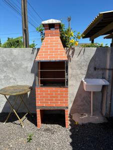 a small brick oven with a sink and a table at Chalé de 2 quartos, com estacionamento, a 5 min da praia! in Passo de Torres