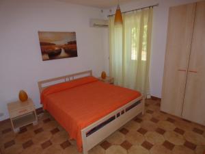 1 dormitorio con 1 cama con colcha de color naranja en Villa Maria, en Patti