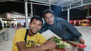 two men sitting at a table with a plate of food at navaa Bungalow in Phra Ae beach