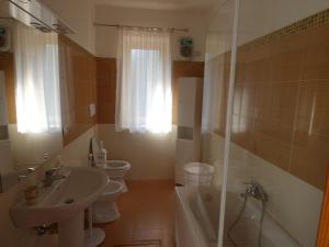 łazienka z 2 toaletami, umywalką i prysznicem w obiekcie Villa Maria w mieście Patti