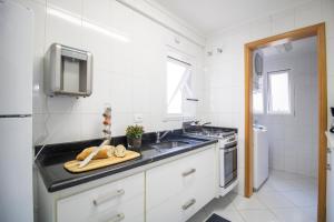cocina blanca con fregadero y fogones en 3 Quartos | Aconchegante | Ótima Localização, en Campos do Jordão