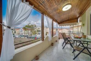 Un balcón con mesa y sillas y una gran ventana. en Veranda Verde in Argostoli, en Argostoli