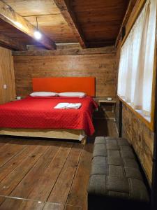Cette chambre en bois comprend un lit rouge. dans l'établissement cabañas en zacatlan, à Zacatlán