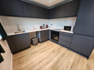 een keuken met zwarte kasten en een houten vloer bij Manchester Extended Stay Apartments in Manchester