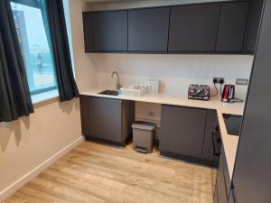 una pequeña cocina con fregadero y encimera en Manchester Extended Stay Apartments, en Mánchester