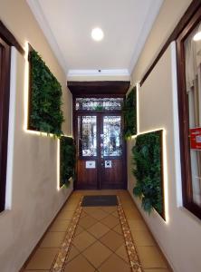 a hallway with a door with plants on the walls at Hotel Raymipampa in Cuenca