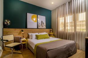 a bedroom with a bed and a chair and a window at Dizengoff square boutique - aparthotel in Tel Aviv