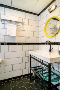 a white tiled bathroom with a sink and a mirror at Dizengoff square boutique in Tel Aviv