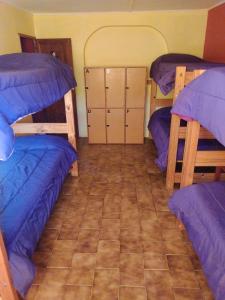 a room with three bunk beds and a tile floor at Hostel Wenuy- in El Chalten